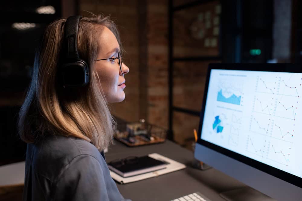 A woman with headphones gazes intently at a computer screen, immersed in overcoming SaaS customer service challenges through outsourcing